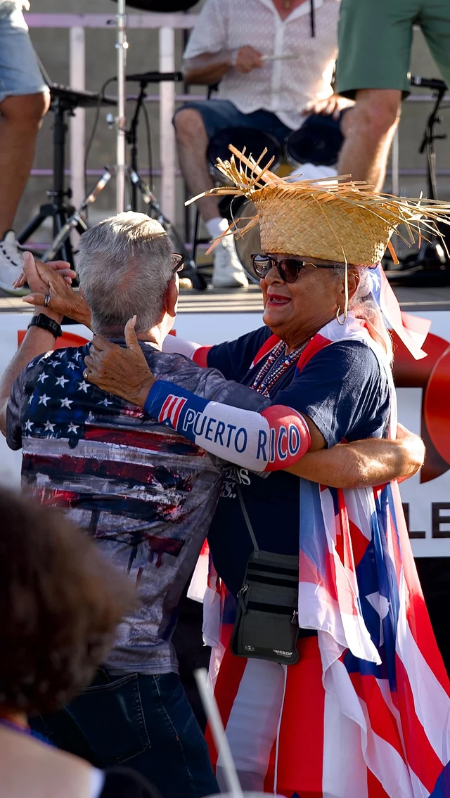 A reel cover of a couple dancing in Puerto Rico-themed clothing at an outdoor festival
