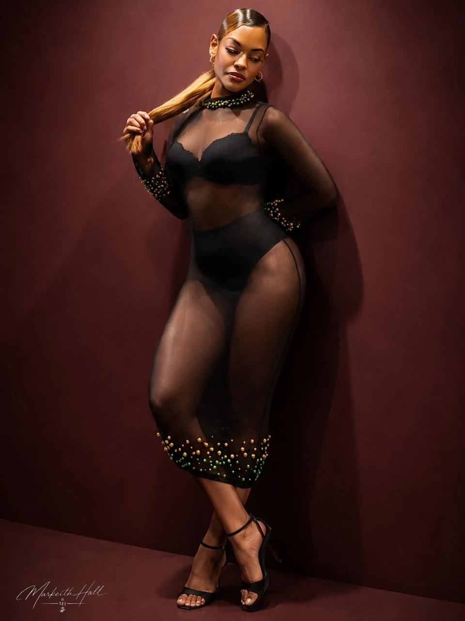A full-length fashion portrait against a burgundy studio backdrop