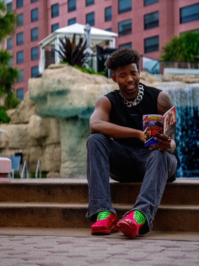 A man reading a 4 Corners comic beside an outdoor fountain