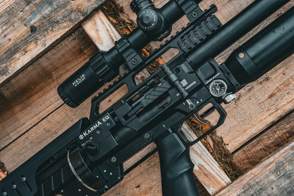 Karma airgun and scope arranged diagonally against weathered wood