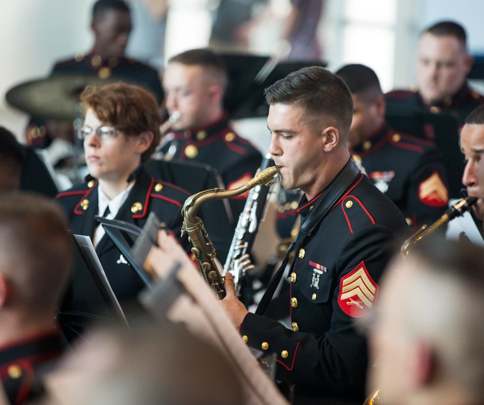 A saxophonist in a Marine band framed among fellow musicians