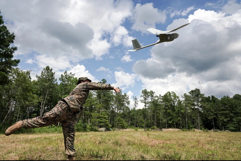 A Marine launches a small aircraft into a cloud-filled sky during field training