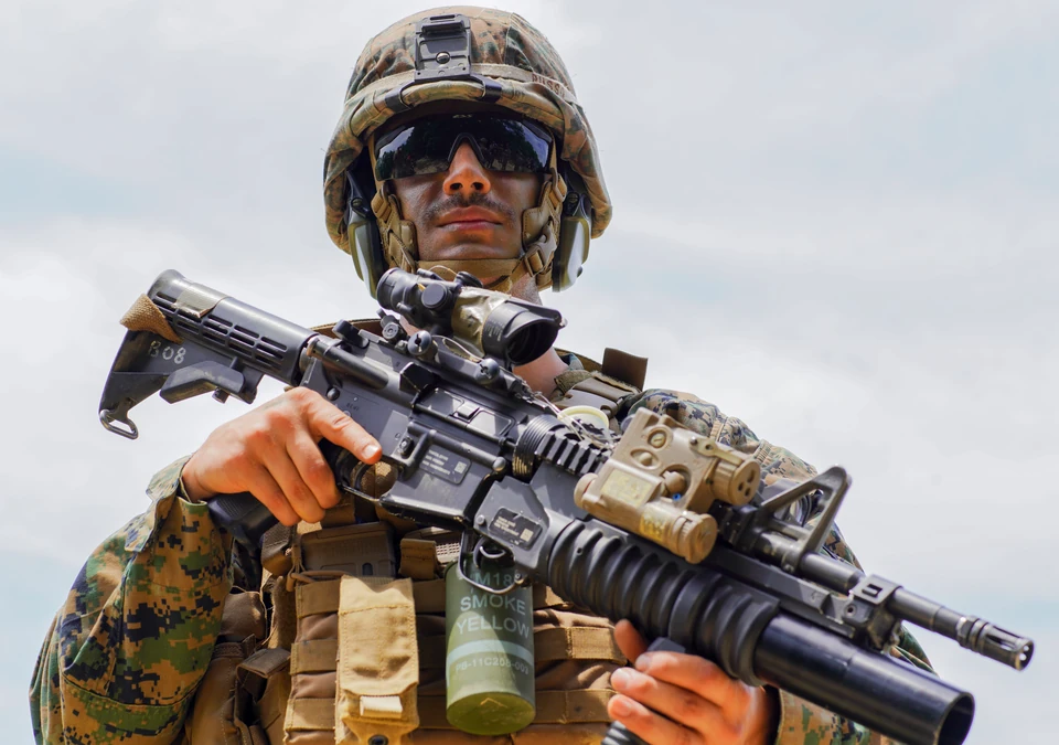 Low-angle portrait of a Marine in field equipment beneath a pale sky